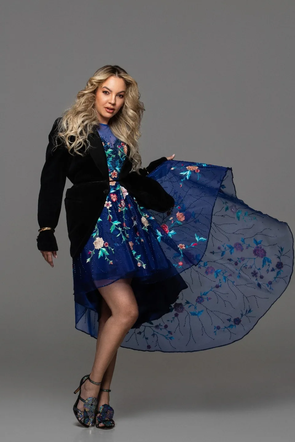 Roberta Graciana em movimento, com vestido azul bordado e blazer preto