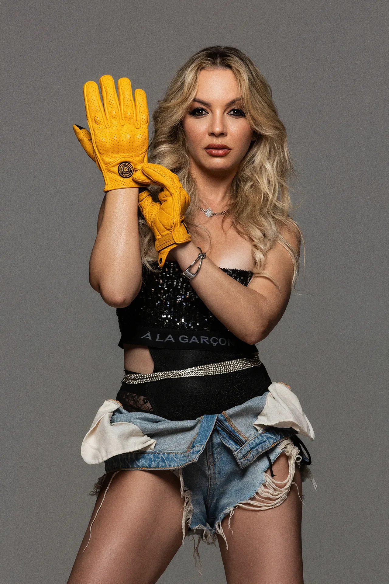 Roberta Graciana com top de lantejoulas, shorts jeans e luvas amarelas de moto
