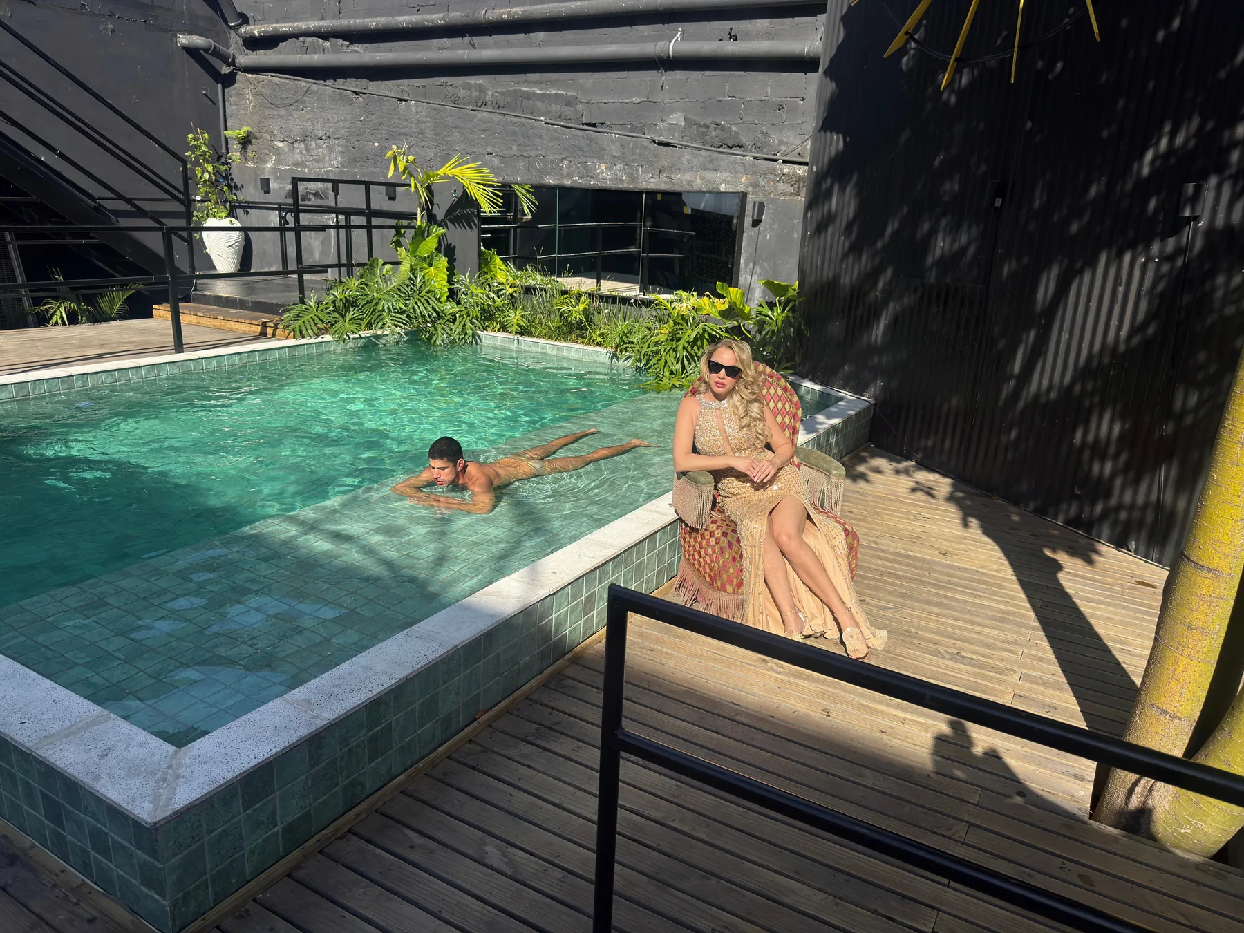 Roberta Graciana em poltrona de vime à beira de uma piscina, em editorial